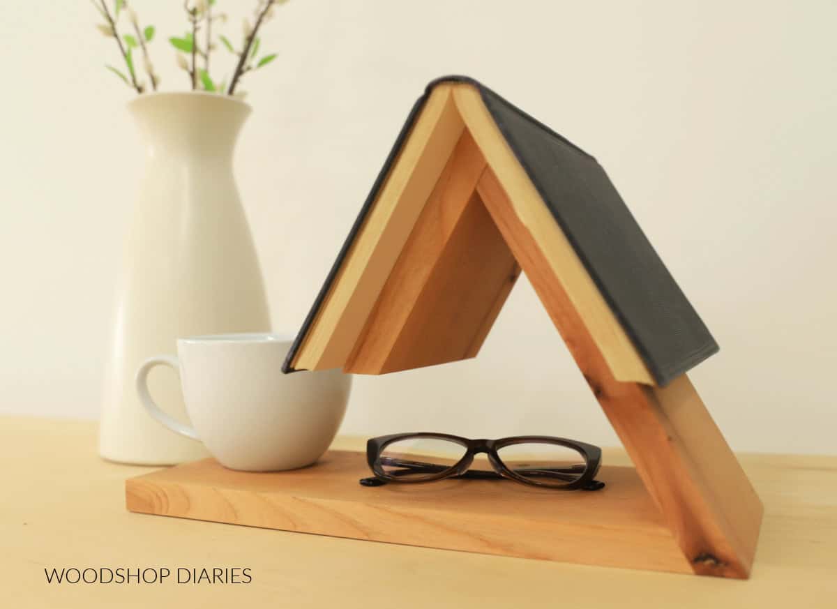 Book holder on side table with book a cup mug and glasses