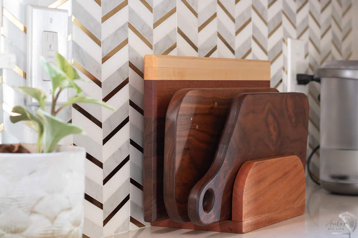 side view of cutting board stand ion the kitchen counter with walnut cutting boards on it.