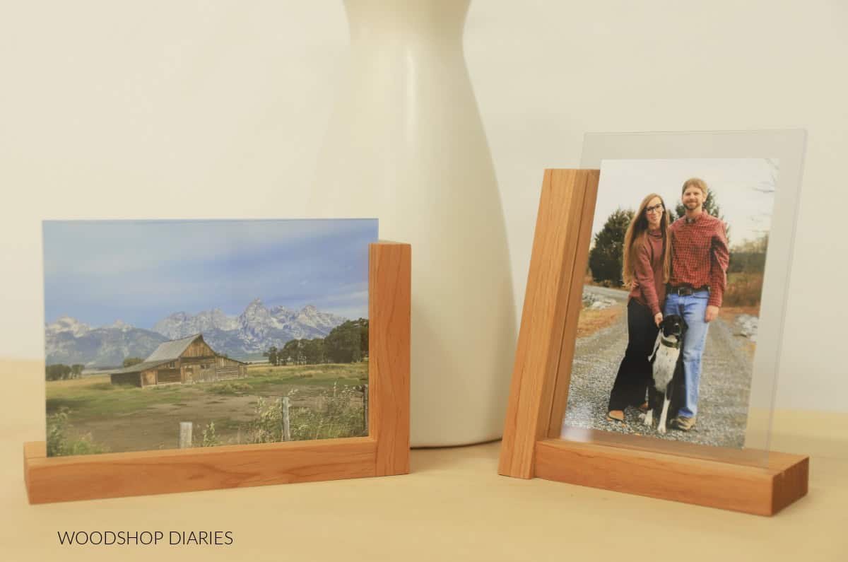 two modern picture frames sitting on desk in front of a vase