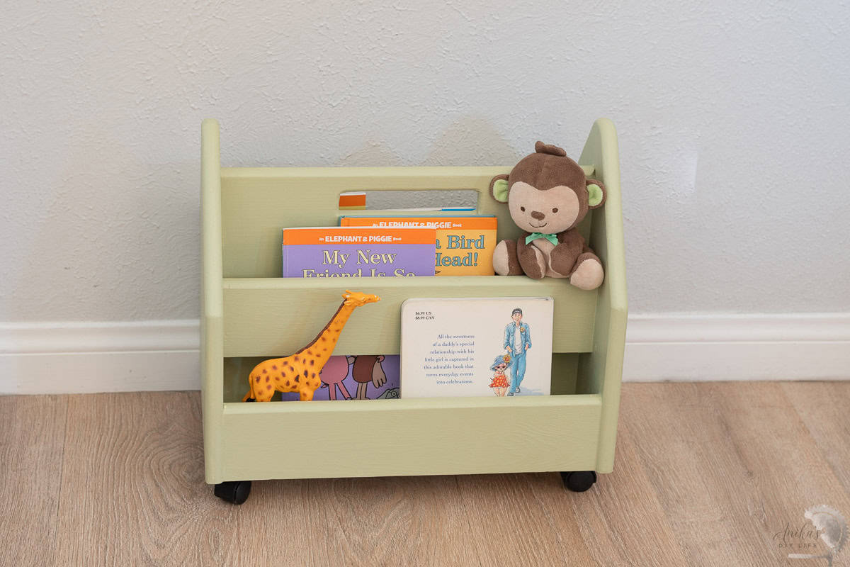 green montessori book wagon with books and a stuffed animal