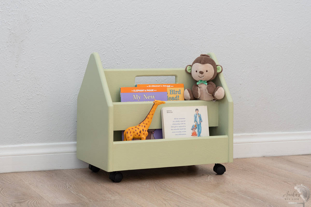 Green montessori bookshelf with books and toys in it
