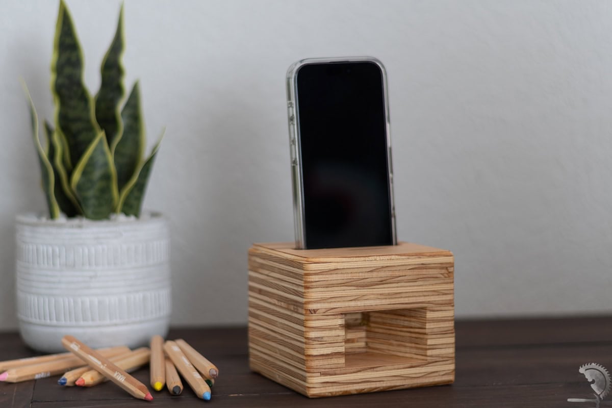 plywood phone amplifier on a desk with pencils and a plant