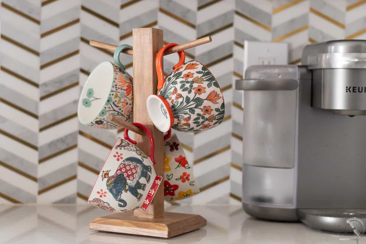 DIY coffee mug tree with colorful cups on a kitchen counter next to a coffee machine