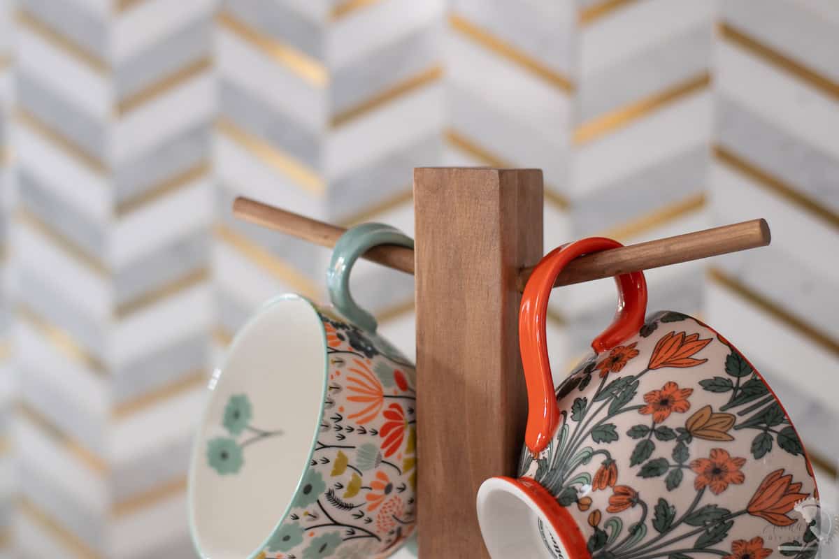 Close up of the diy mug tree showing angled dowels with colorful mugs on it
