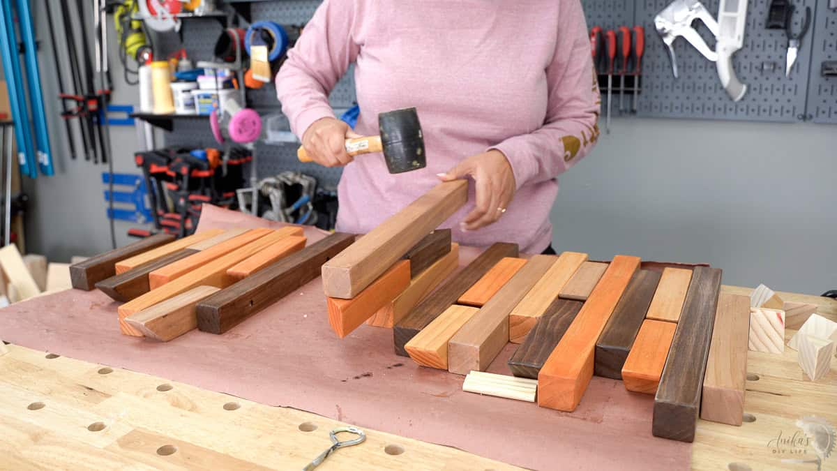 Assembling the DIY coat rack by adding the pieces on dowels with a mallet