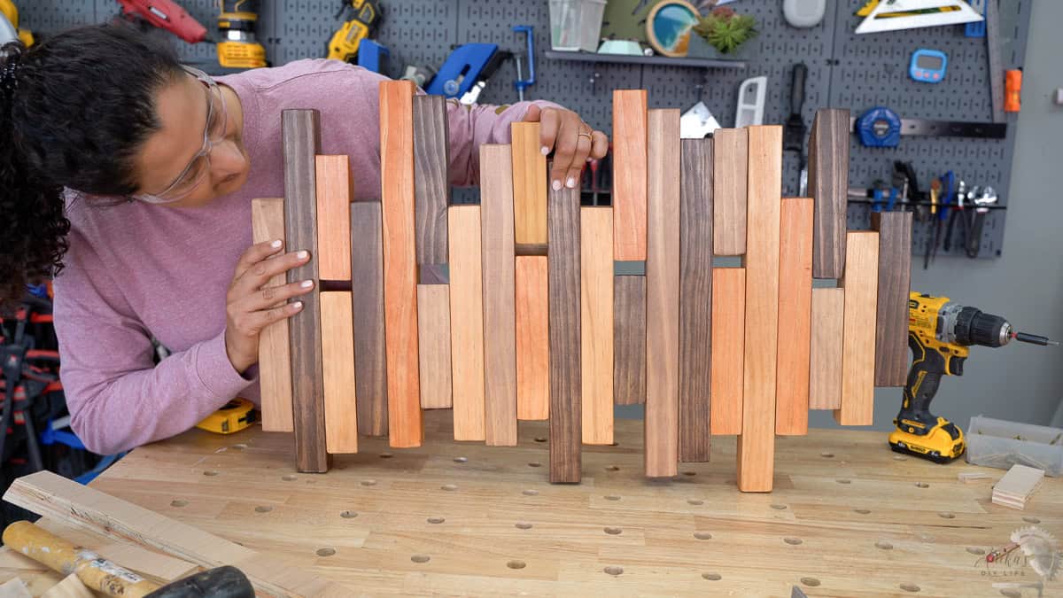 Anika holding a finished modern coat rack with multiple colored stains