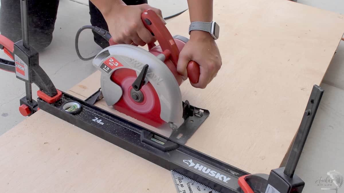 woman cutting plywood using a circular saw and level as a guide