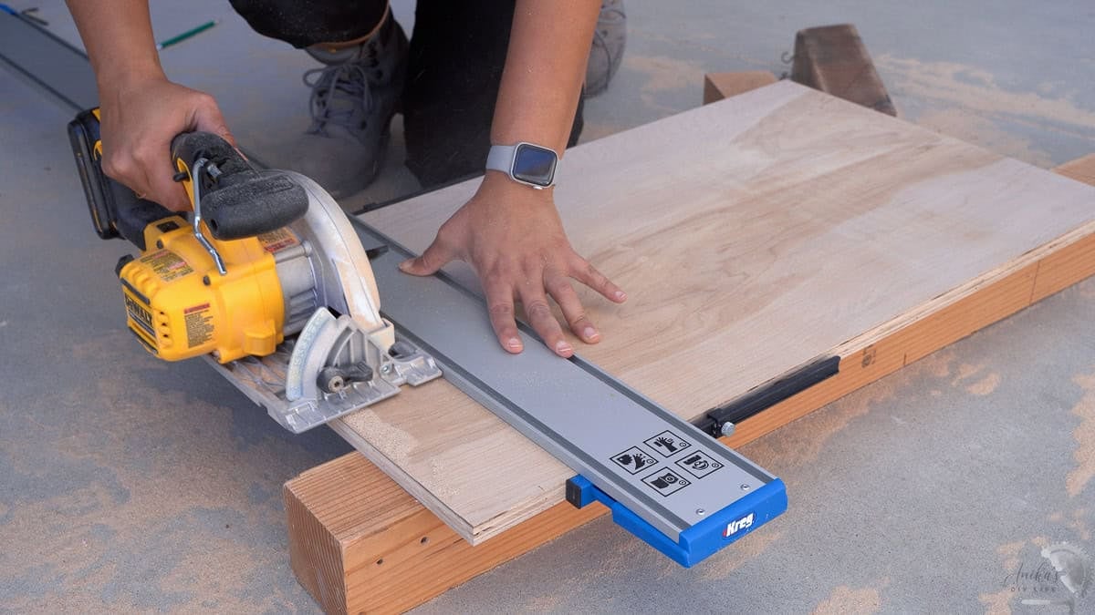 Using a straight edge guide to guide the circular saw and cut plywood