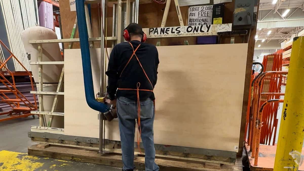 worker cutting plywood on a panel saw in a big box store