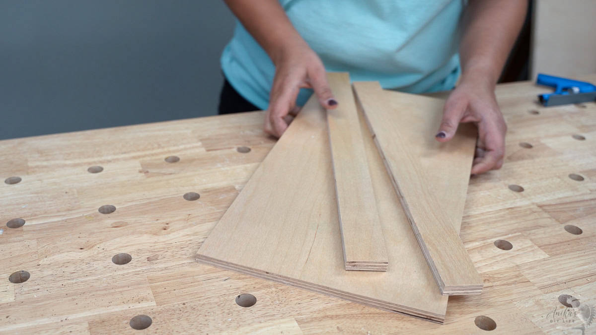 Woman holding pieces of plywood on a workbench