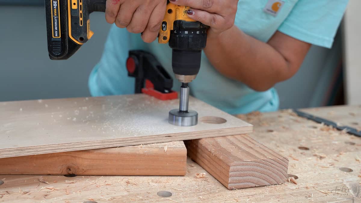 Anika drilling the holes using a forstener bit with a drill