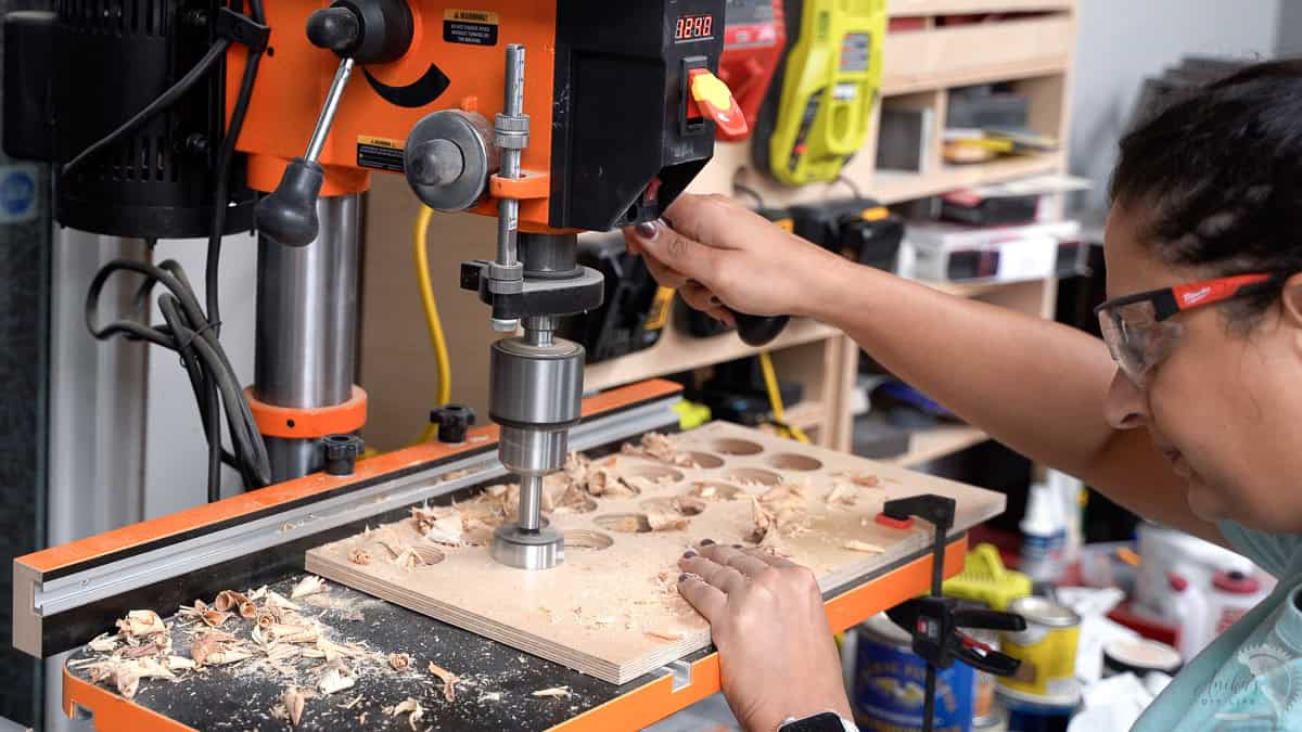 Anika drilling the holes using a forstener bit with a drill press