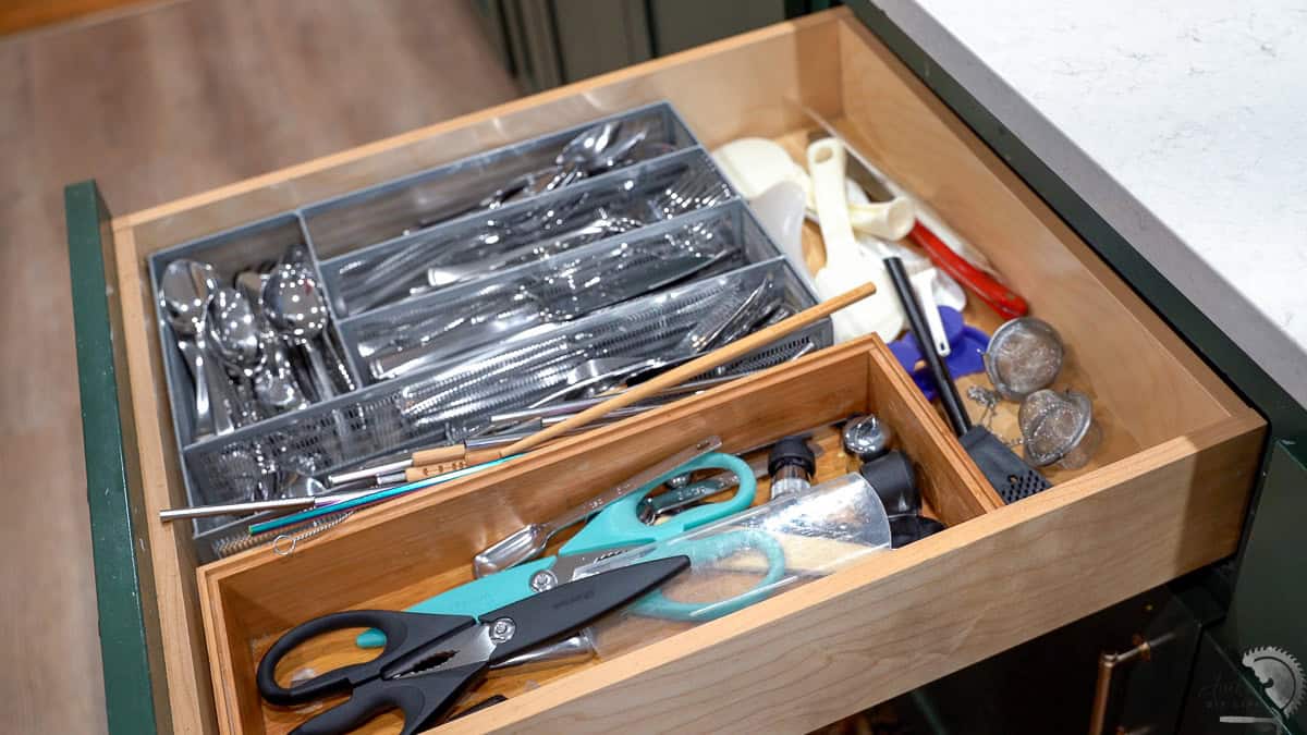 A kitchen drawer full of mismatched organizers and clutter.