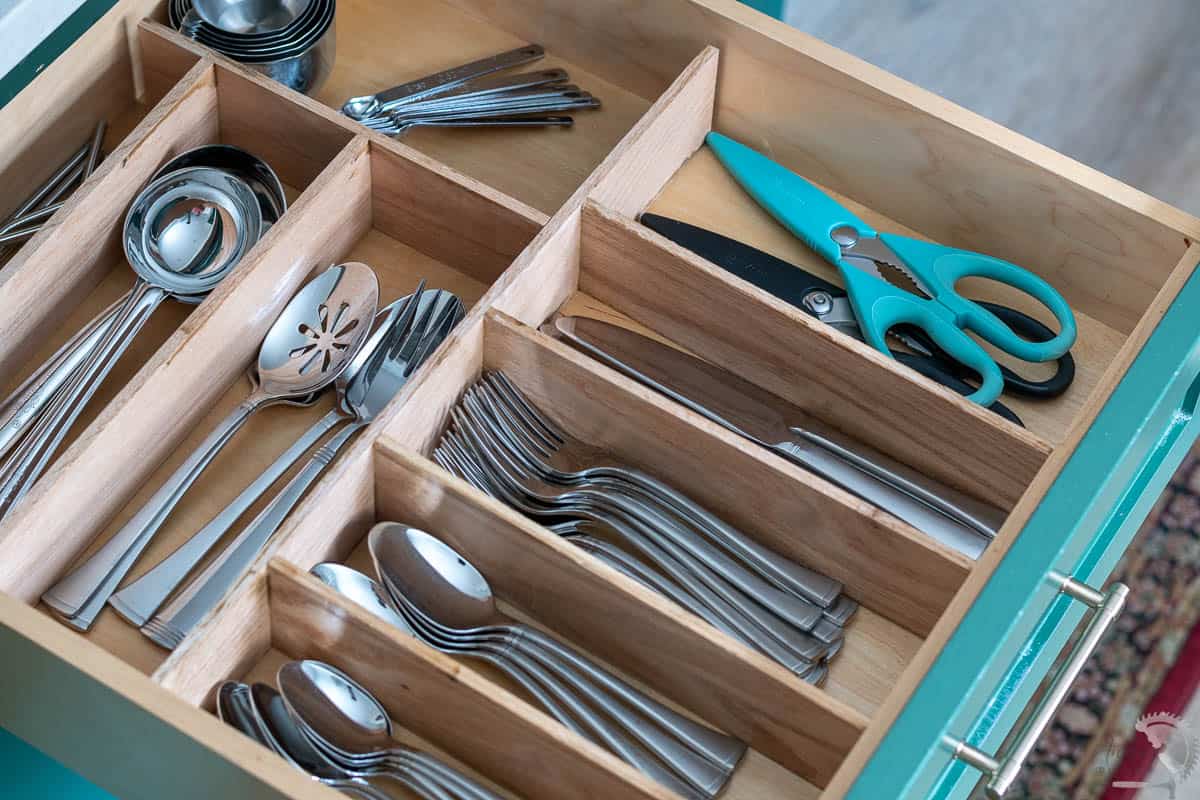 Custom wooden DIY kitchen drawer organizer in a green cabinet drawer with silverware organized