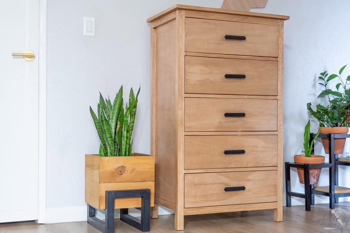 Side view of the DIY dresser with 5 drawers in a room next to a planter with plants