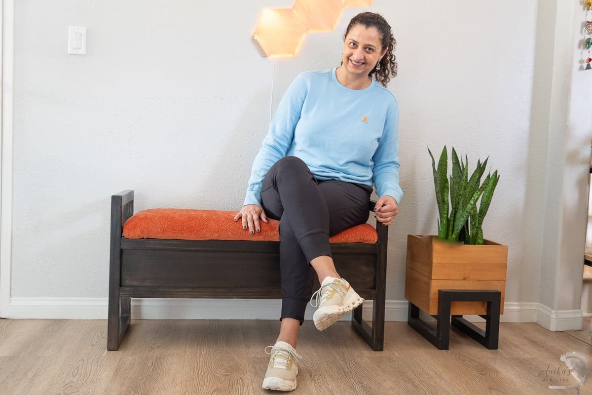 Anika sitting on the DIY Upholstered storage bench