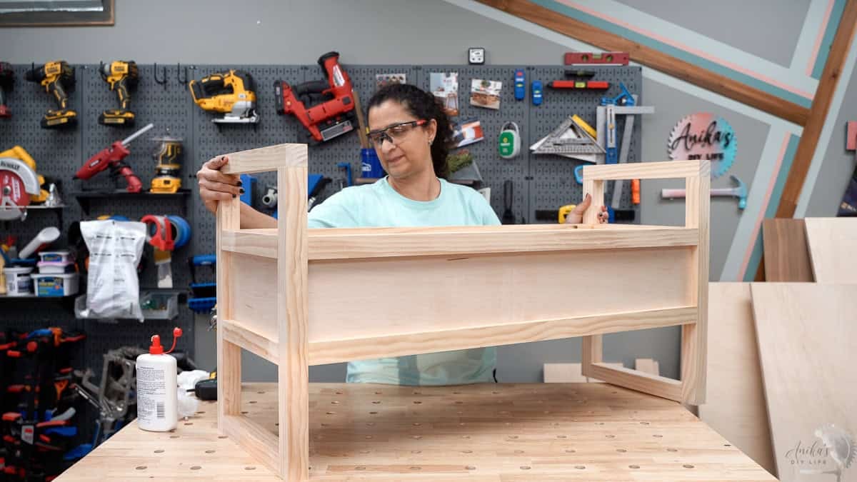 Anika holding the diy storage bench built on the workbench