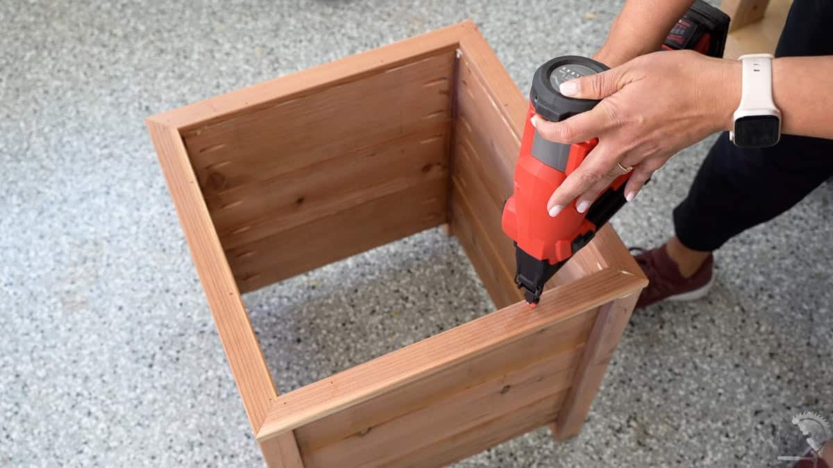 Attaching 1x2 trim on top of the planter with a nail gun
