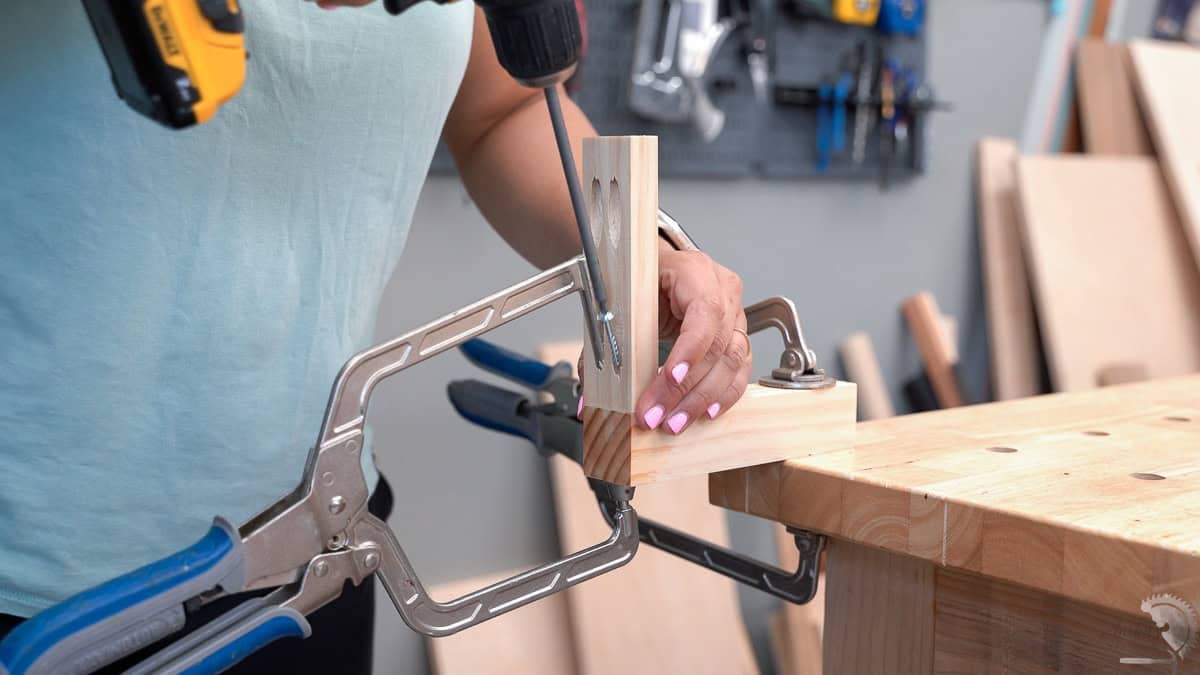Using a clamp to hold boards together as a pocket hole screw is driven into a pocket hole.
