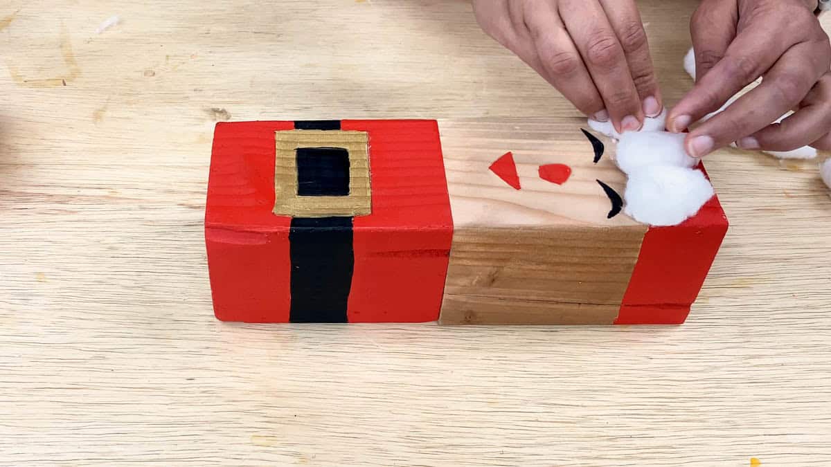 Adding cotton to the top block to finish Santa's hat