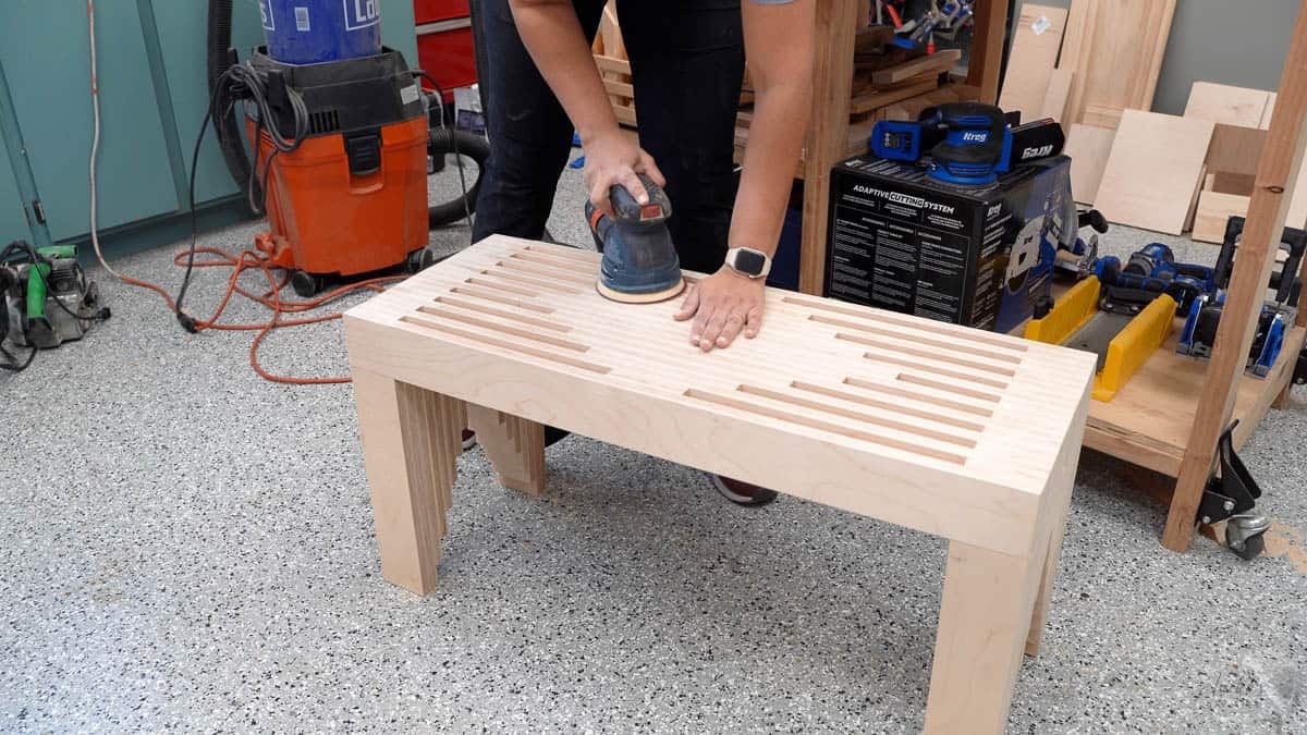 Sanding the bench to make it smooth with a random orbital sander