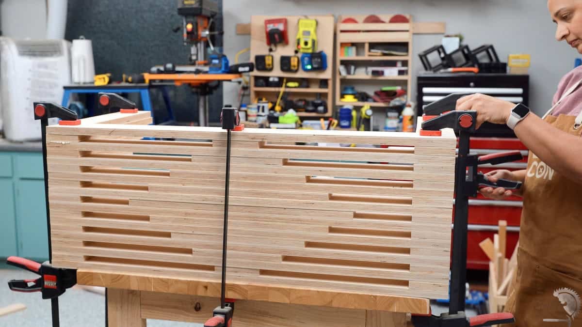 Clamping the layers of the plywood bench together on the workbench in the workshop