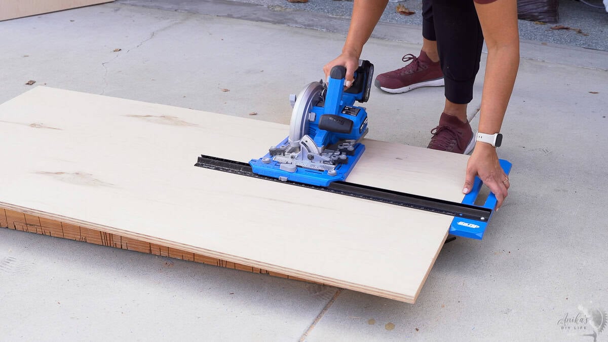 Anika cutting down a sheet of plywood with a circular saw and rip cut
